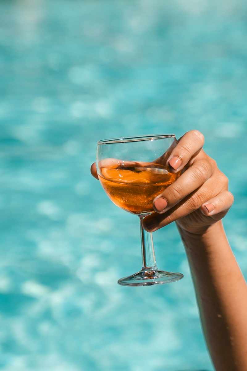 Glass of wine being held up with a swimming pool background